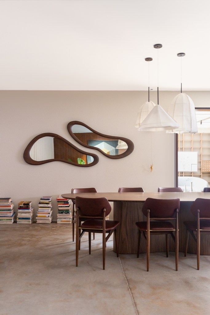 Salas de 60 m² celebram momentos em família e design brasileiro. Projeto de Maria Araujo para a CASACOR Brasilia 2023. Na foto, sala de jantar com livros e espelho organico.