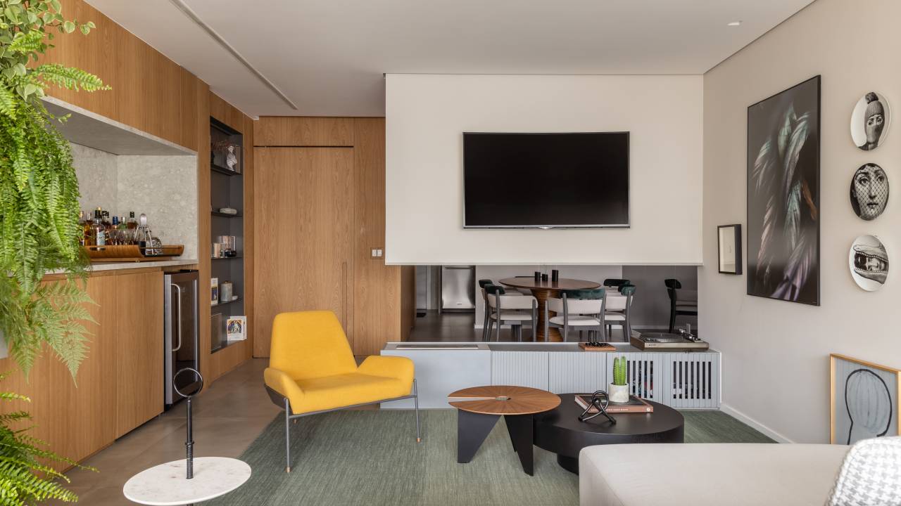 Sofá-ilha divide estar e jantar em apê de 115 m² pensado para os pets. Projeto Si Saccab. Na foto, sala de estar com parede suspensa e lareira.
