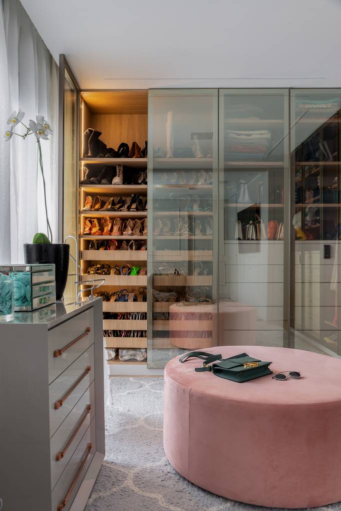 6 Tendências para o closet dos sonhos. Projeto de Spaço Interior. Na foto, closet com portas transparentes e pufe rosa.