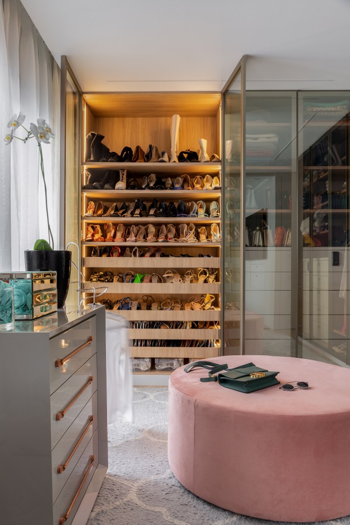 6 Tendências para o closet dos sonhos. Projeto de Spaço Interior. Na foto, closet com portas transparentes e pufe rosa.