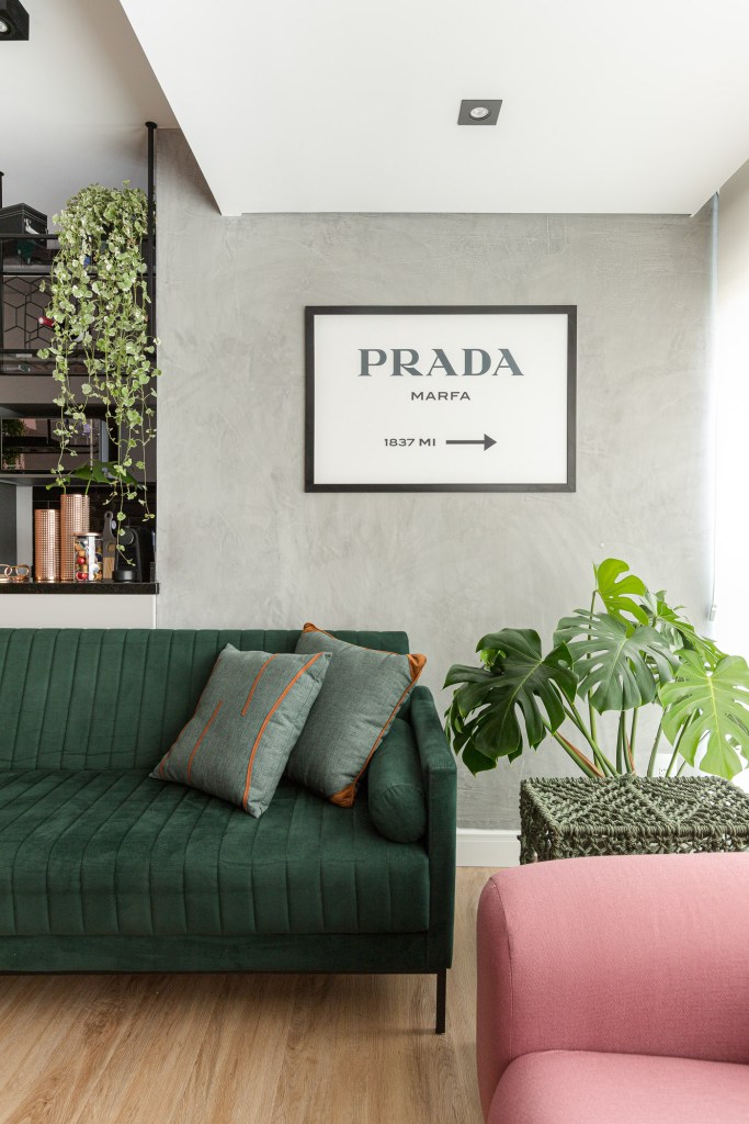 Projeto de Inovando Arquitetura. Na foto, sala com parede de cimento queimado, sofá verde escuro e planta.