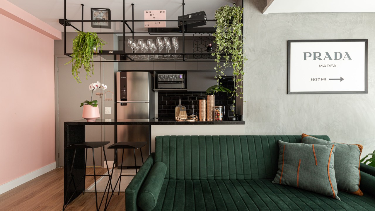 Projeto de Inovando Arquitetura. Na foto, cozinha integrada com bancada e ilha preta e sofá verde escuro.