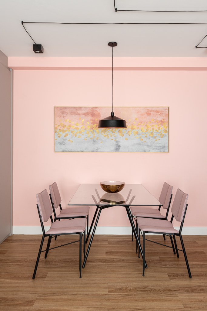 Projeto de Inovando Arquitetura. Na foto, sala de jantar pequena com mesa de tampo de vidro, cadeiras e parede rosas.
