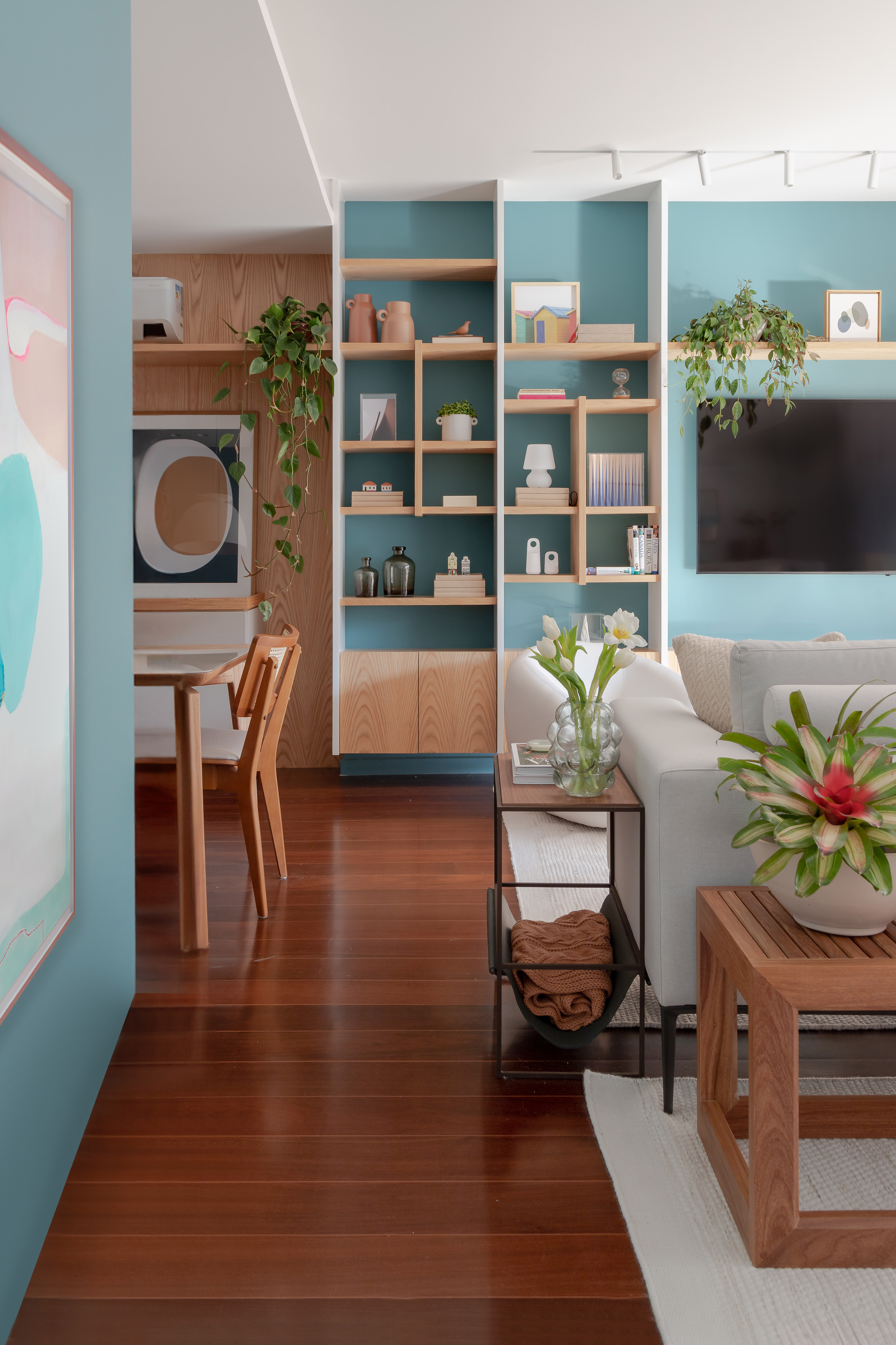 Projeto de MR Arquitetura. Na foto, sala de estar integrada com jantar com parede azul e estante vazada com nichos.