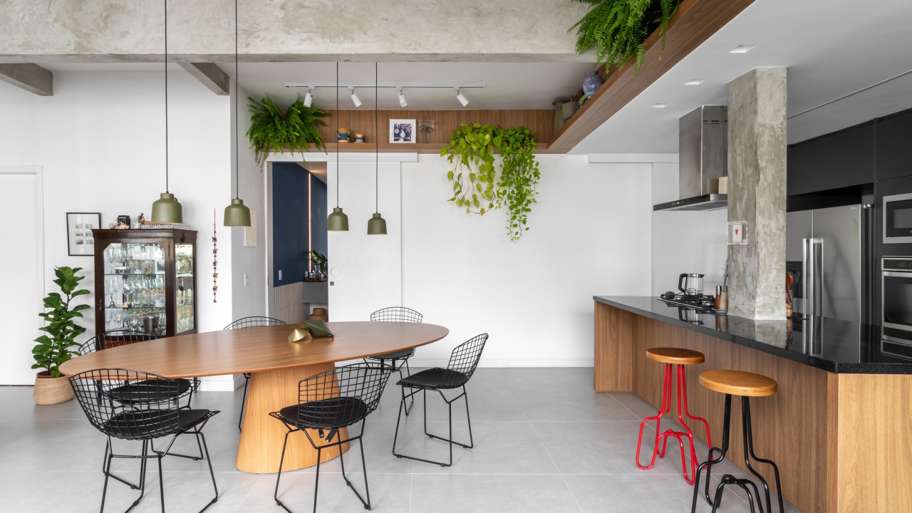 Projeto de Raphael Assaf Arquitetura. Na foto, cozinha integrada com sala de jantar. Mesa de madeira, prateleiras com plantas e piso de porcelanato.