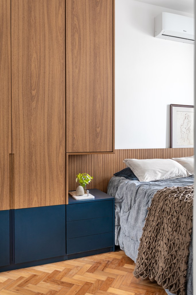 Projeto de Raphael Assaf Arquitetura. Na foto, cama com cabeceira ripada, armário com meia pintura azul marinho.