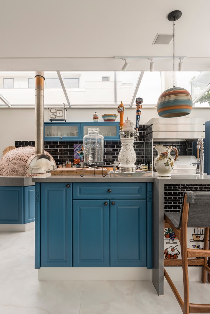 Projeto de PB Arquitetura. Na foto, cozinha em estilo shaker com marcenaria azul e teto com cobertura transparente.