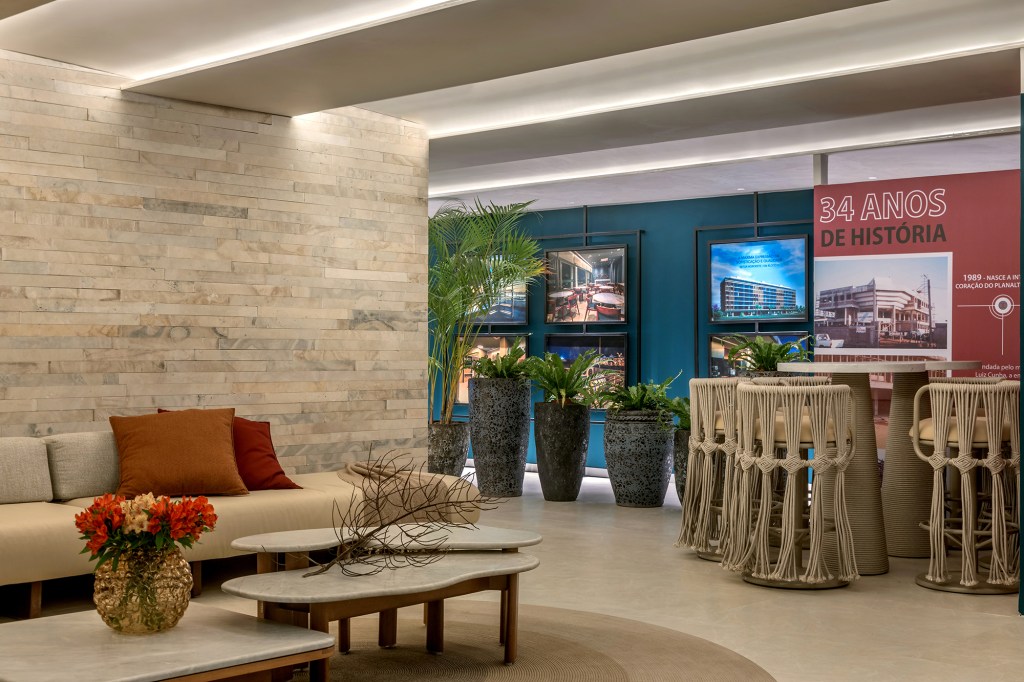 Apartamento de 189 m² tem décor afetivo e repleto de peças autorais. Projeto de Vivian Maia para a CASACOR Brasília 2023. Na foto, sala com parede de pedra, azul e cadeiras de fibra.