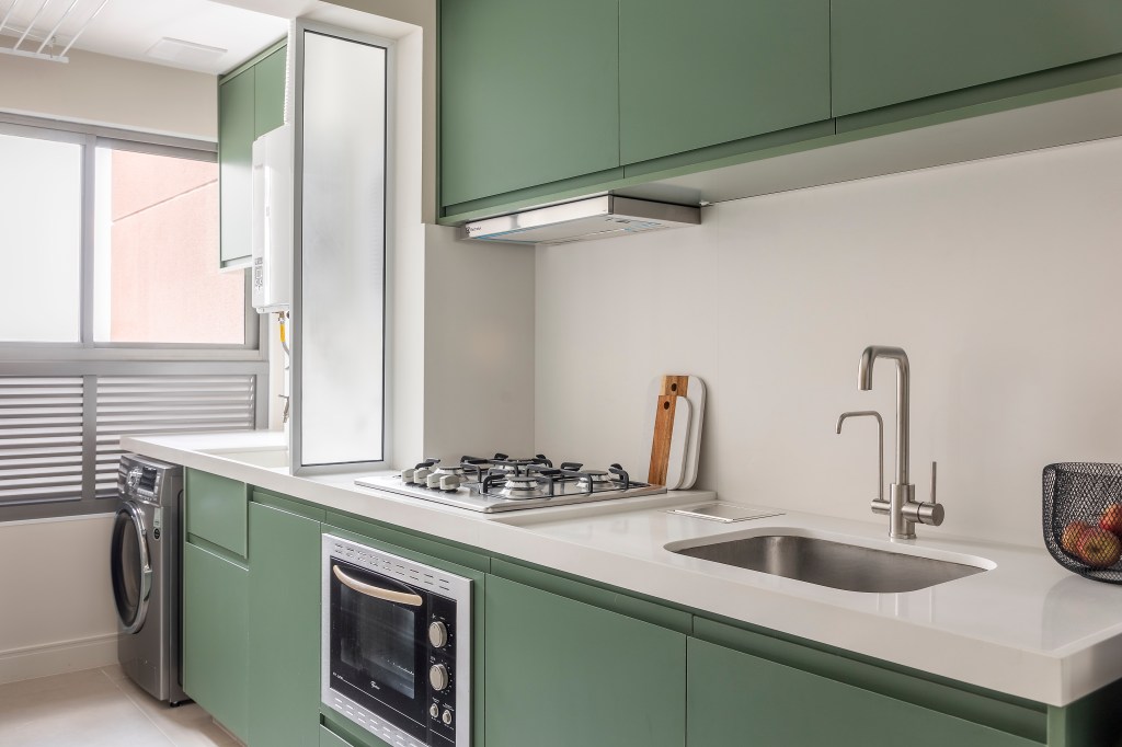 Projeto de Andrea Balastreire. Na foto, cozinha verde menta com lavanderia integrada.