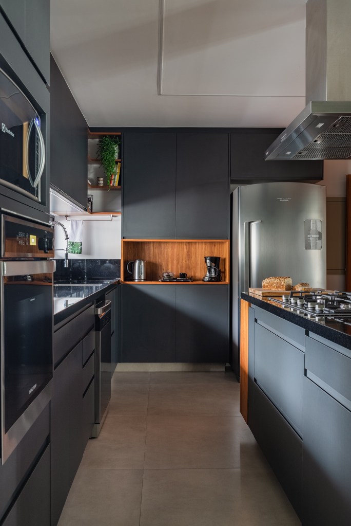 Projeto de Adriana Bersou. Na foto, cozinha integrada com marcenaria preta.