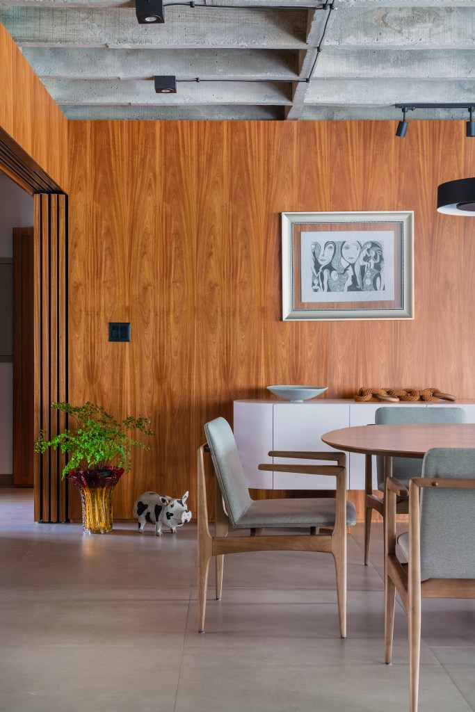 Projeto de Adriana Bersou. Na foto, sala de jantar com parede revestida de madeira.