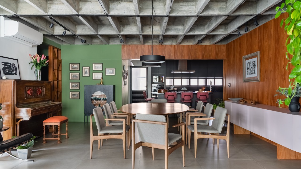 Projeto de Adriana Bersou. Na foto, sala de estar e jantar integradas com laje de concreto aparente e parede verde.