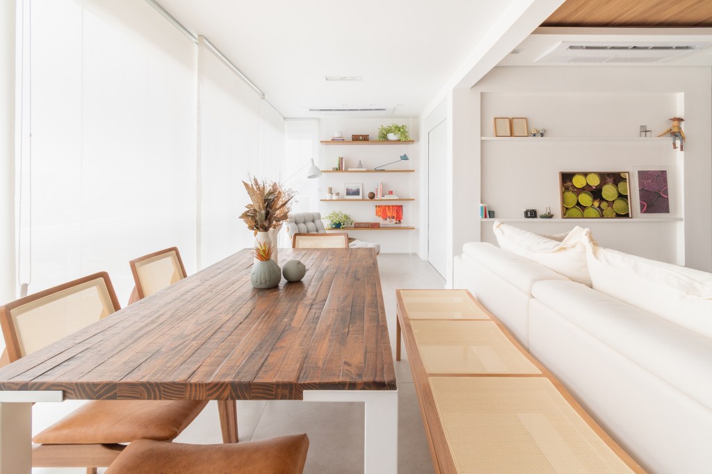 Apê minimalista de 100 m² foi pensado para os quatro cachorros da família. Projeto de Entre Studio. Na foto, varanda com espaço gourmet. poltrona de leitura e sala integrada.