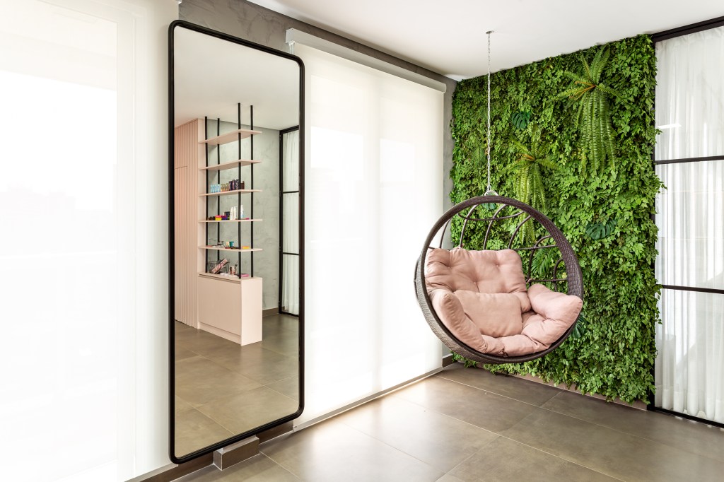 Ateliê de maquiagem de 50 m² une ripado, poltrona suspensa e jardim vertical. Projeto de Larissa Cabral.