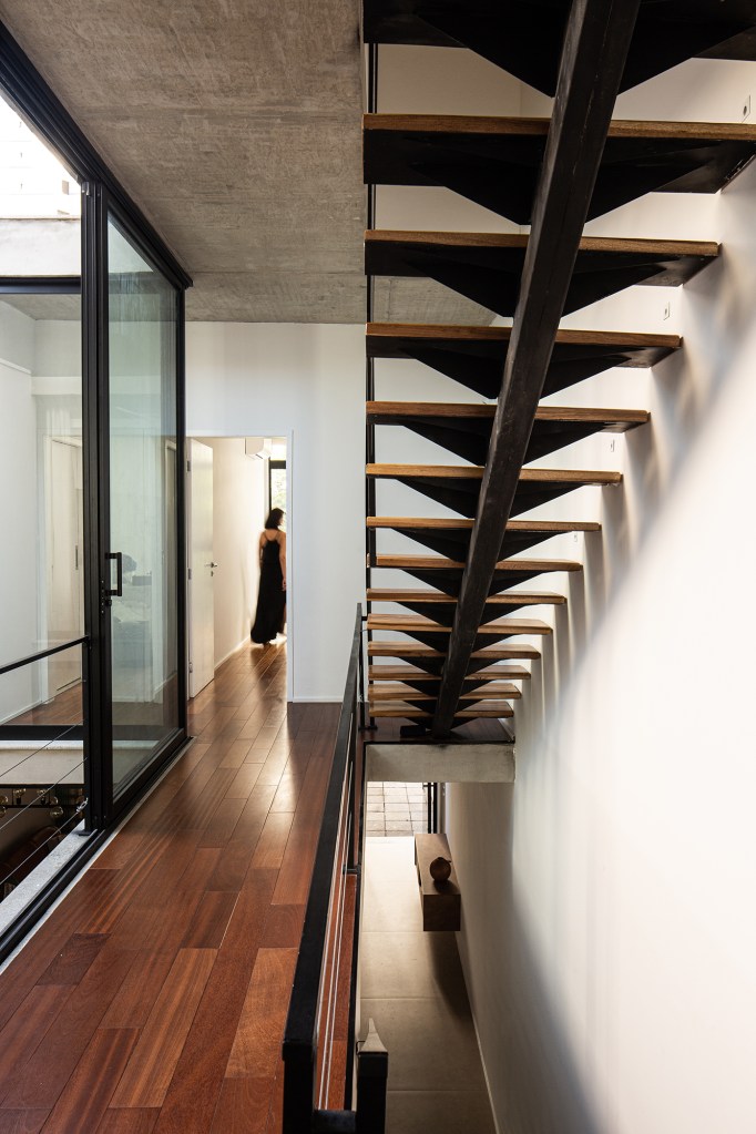 Átrio central e fachada vazada de tijolos marcam projeto de casa de 220 m². Projeto Eixo Arquitetos. Na foto, escada vazada com aberturas externas.