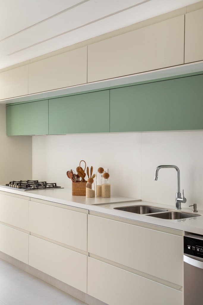 Projeto de Beta Arquitetura. Na foto, cozinha clara com marcenaria off white e detalhe verde.