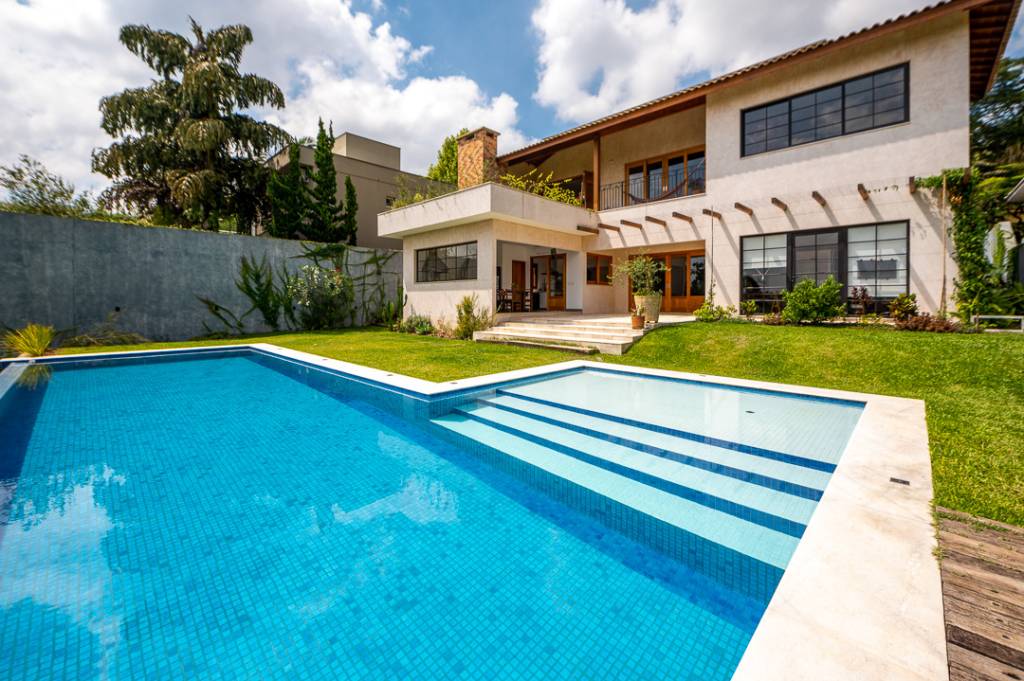 Casa de campo de 450 m² tem dois estúdios e vista para a natureza. Projeto de Geração Arquitetura. Na foto, fachada da casa com jardim e piscina,