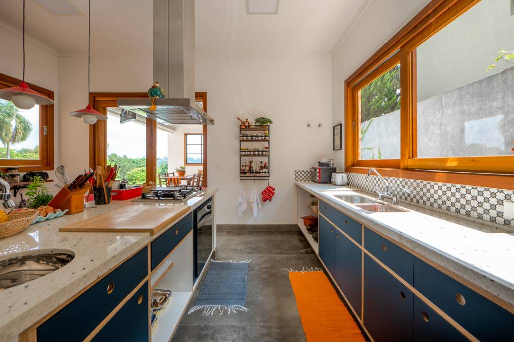 Casa de campo de 450 m² tem dois estúdios e vista para a natureza. Projeto de Geração Arquitetura. Na foto, cozinha com ilha, backsplash geométrico e cadeiras vermelhas.