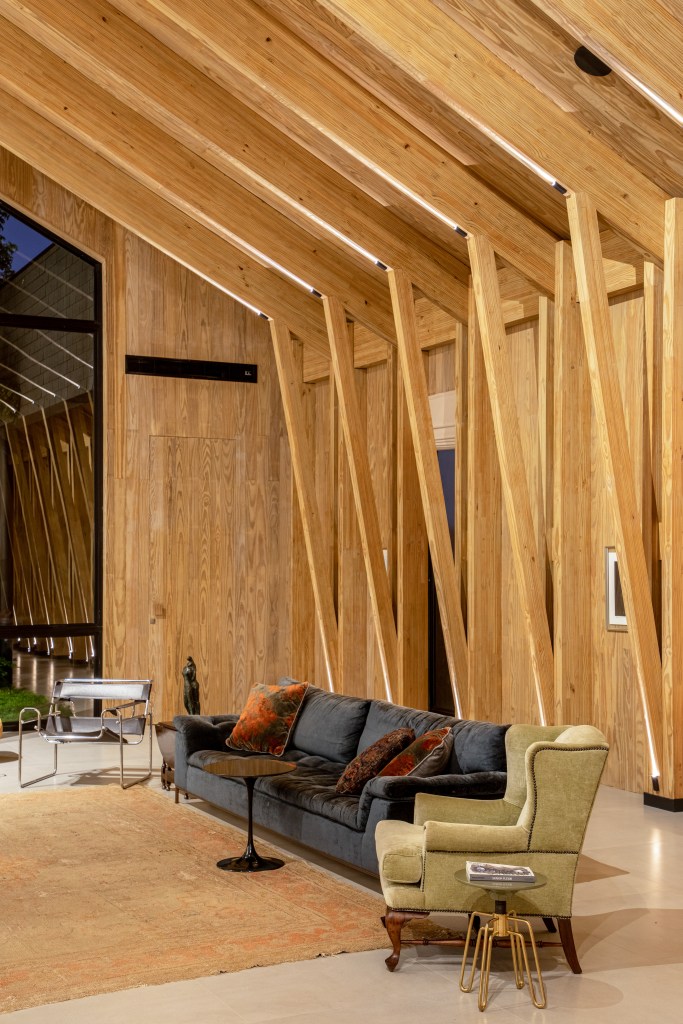 Casa celeiro de madeira une o rústico e o moderno em projeto de 1230 m². Projeto de Otto Felix. Na foto, sala de estar com estrutura de madeira e sofá.