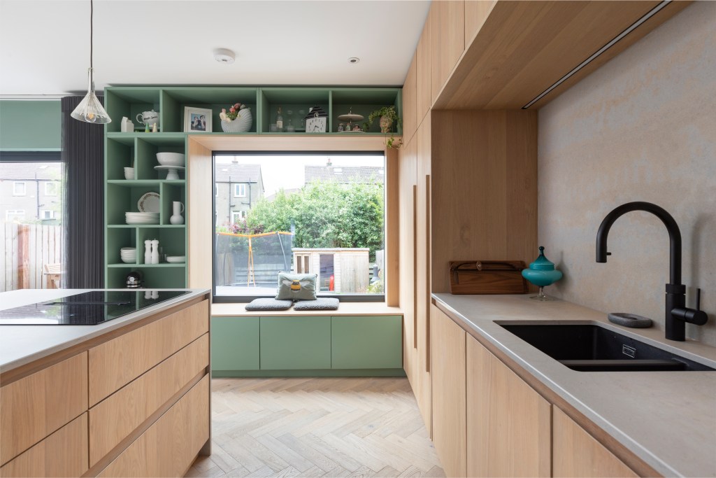 Projeto de AGORA architecture + design. Na foto, cozinha com eletrodomésticos escondidos na marcenaria. Estante verde com nichos.