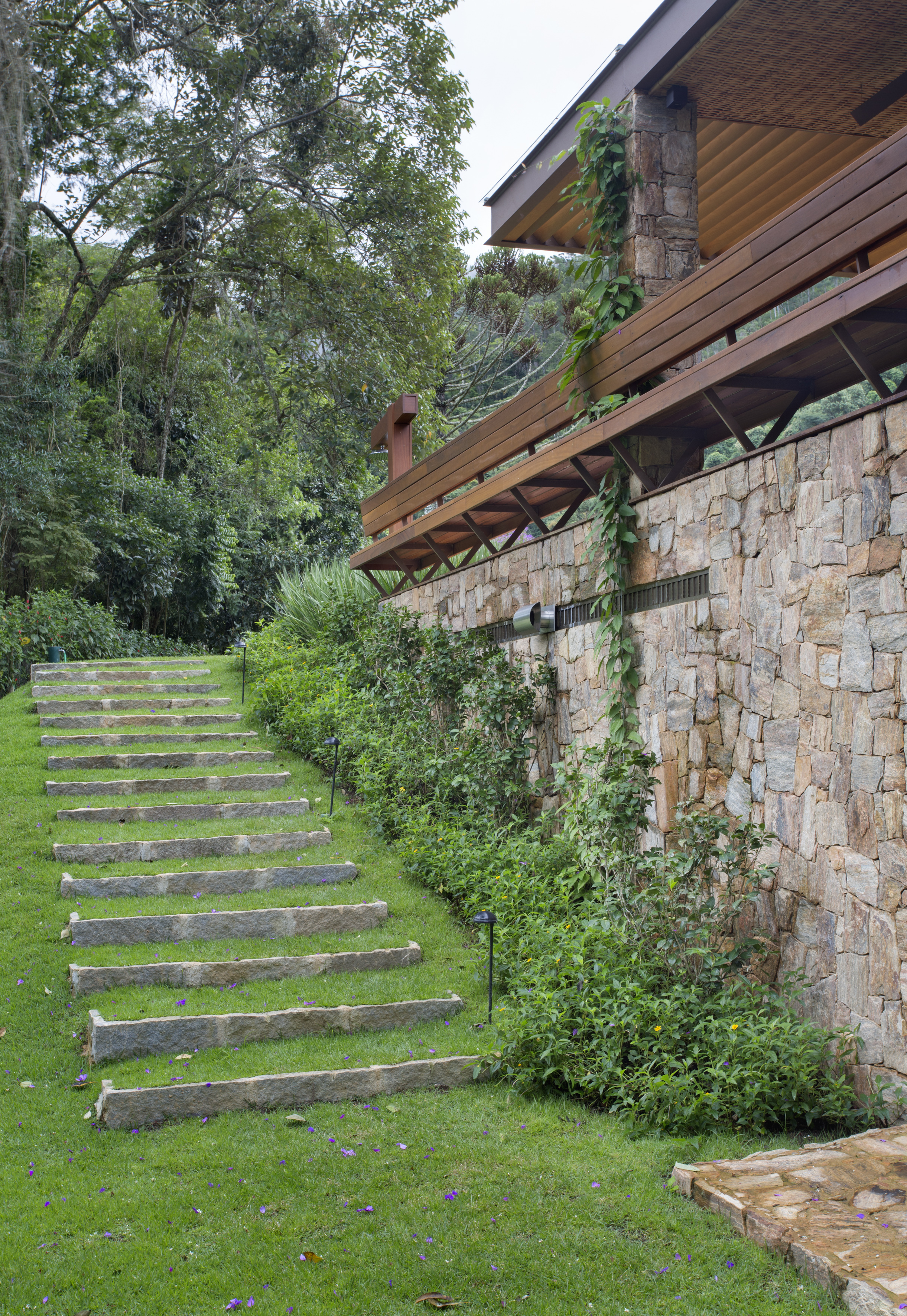 Casa de campo ganha churrasqueira com fogão à lenha e varanda de estar. Projeto de Escala Arquitetura. Na foto, escada em jardim.