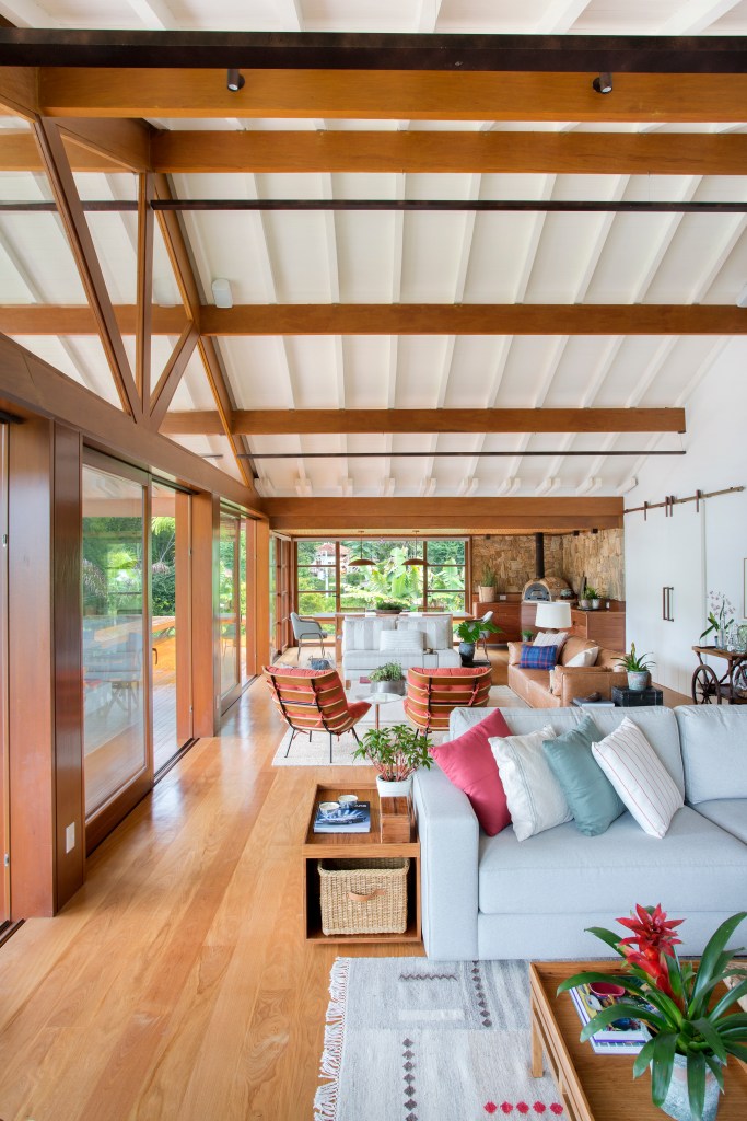 Casa de campo ganha churrasqueira com fogão à lenha e varanda de estar. Projeto de Escala Arquitetura. Na foto, sala de estar com sofás brancos.