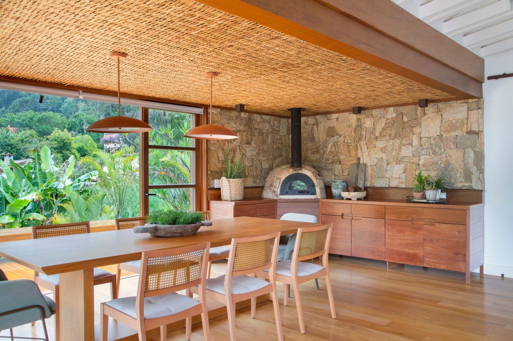 Casa de campo ganha churrasqueira com fogão à lenha e varanda de estar. Projeto de Escala Arquitetura. Na foto, churrasqueira com mesa e forno de pizza.