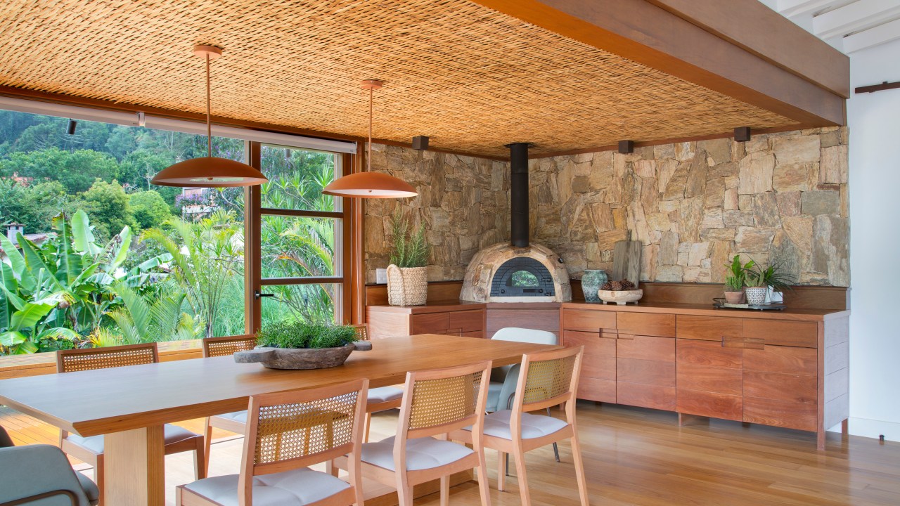 Casa de campo ganha churrasqueira com fogão à lenha e varanda de estar. Projeto de Escala Arquitetura. Na foto, churrasqueira com mesa e forno de pizza.
