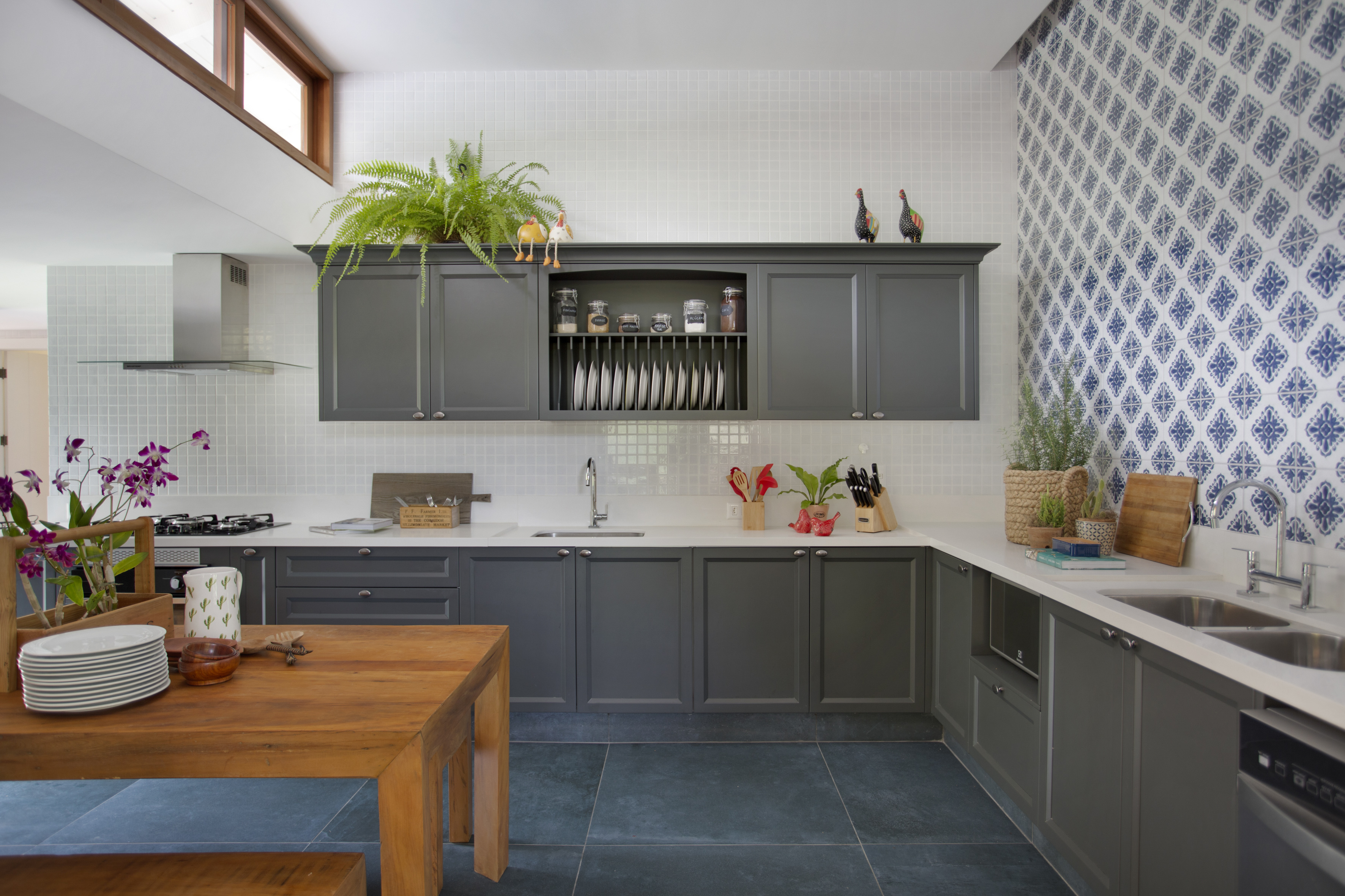 Casa de campo ganha churrasqueira com fogão à lenha e varanda de estar. Projeto de Escala Arquitetura. Na foto, cozinha com piso de azulejo azul e armários cinzas.