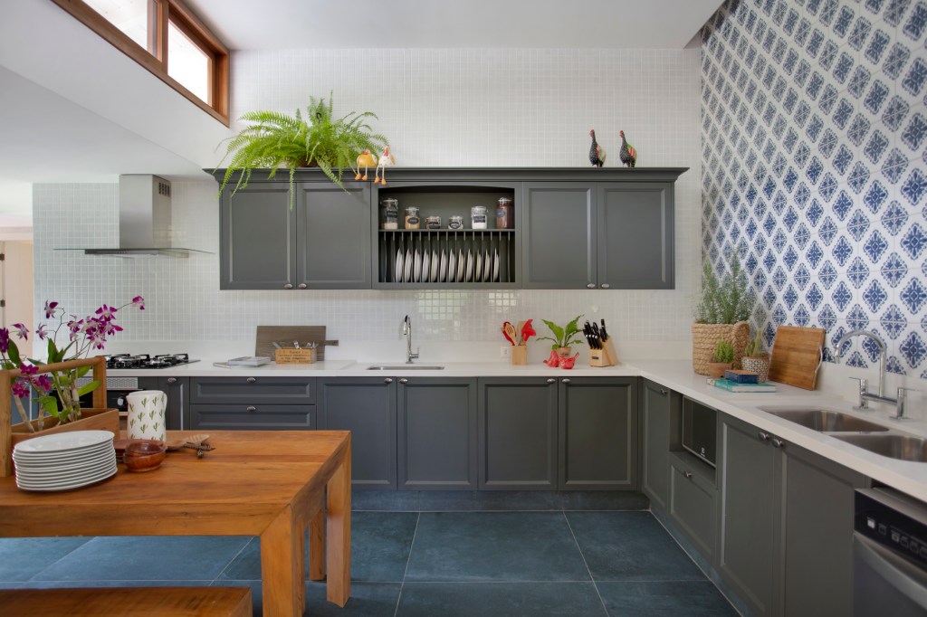Casa de campo ganha churrasqueira com fogão à lenha e varanda de estar. Projeto de Escala Arquitetura. Na foto, cozinha com piso de azulejo azul e armários cinzas.