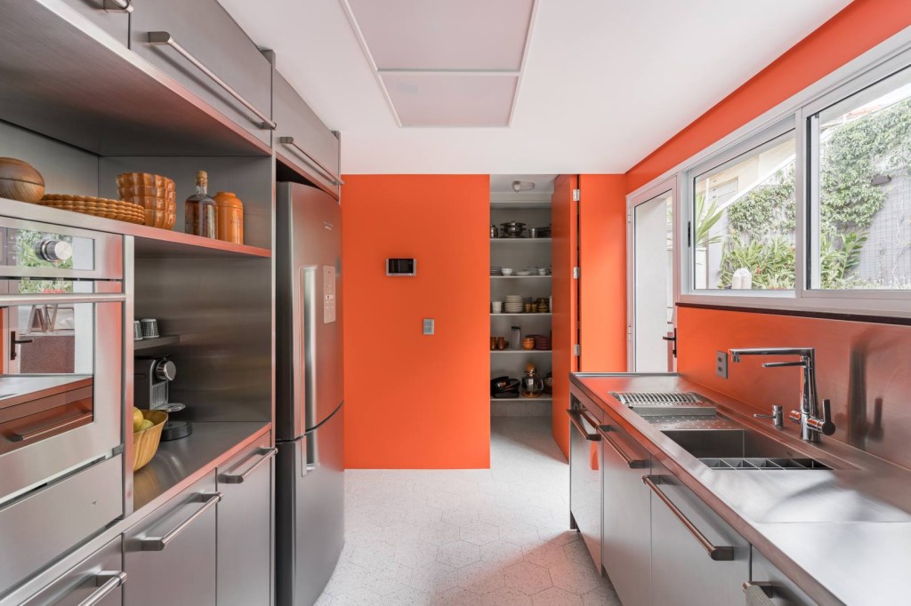 Cozinha ganha projeto moderno com acabamentos em inox e fórmica laranja. Projeto de Bia Hajnal.