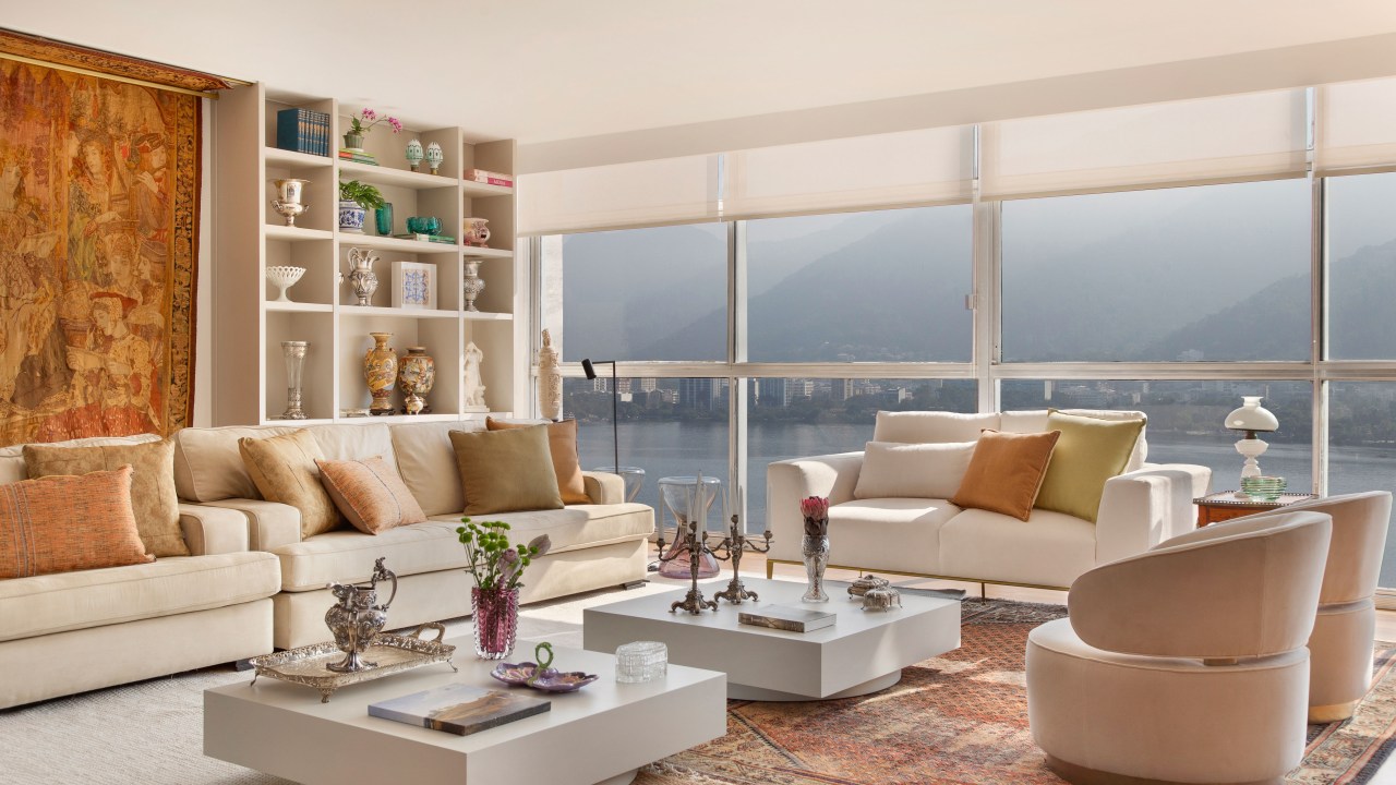 Projeto de Ricardo Melo e Rodrigo Passos. Na foto, sala de estar com sofá branco, tapete e estante de nichos.