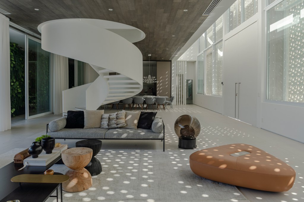 Fachada de muxarabi cria jogo de luz e sombra em casa de 1500 m². Projeto Lovisaro Arquitetura. Na foto, sala com escada helicoidal e muro de muxarabi.