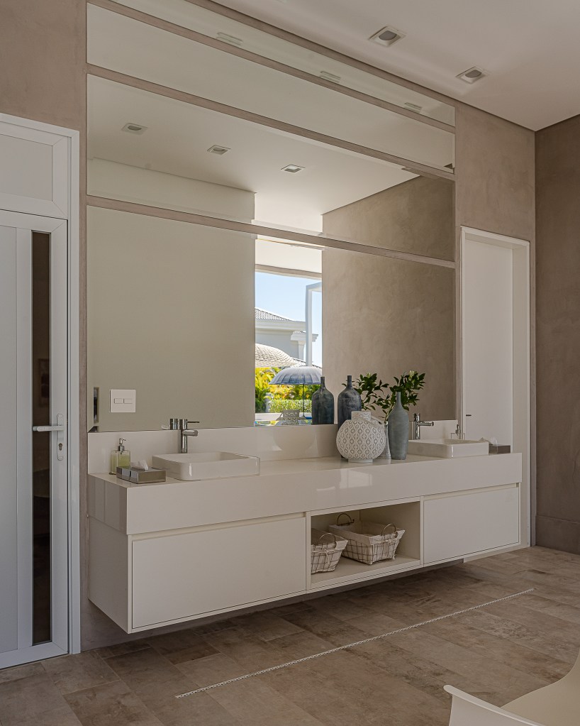 Fachada de muxarabi cria jogo de luz e sombra em casa de 1500 m². Projeto Lovisaro Arquitetura. Na foto, banheiro com pia dupla e espelho.