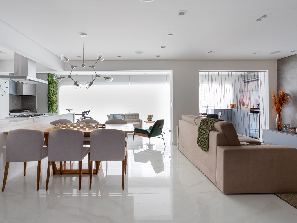Home office ganha destaque na entrada deste apê de 147 m². Projeto de Bruna Bittencourt. Na foto, sala de estar, jantar e varanda integrados. Parede verde, sofá, mesa e poltronas.