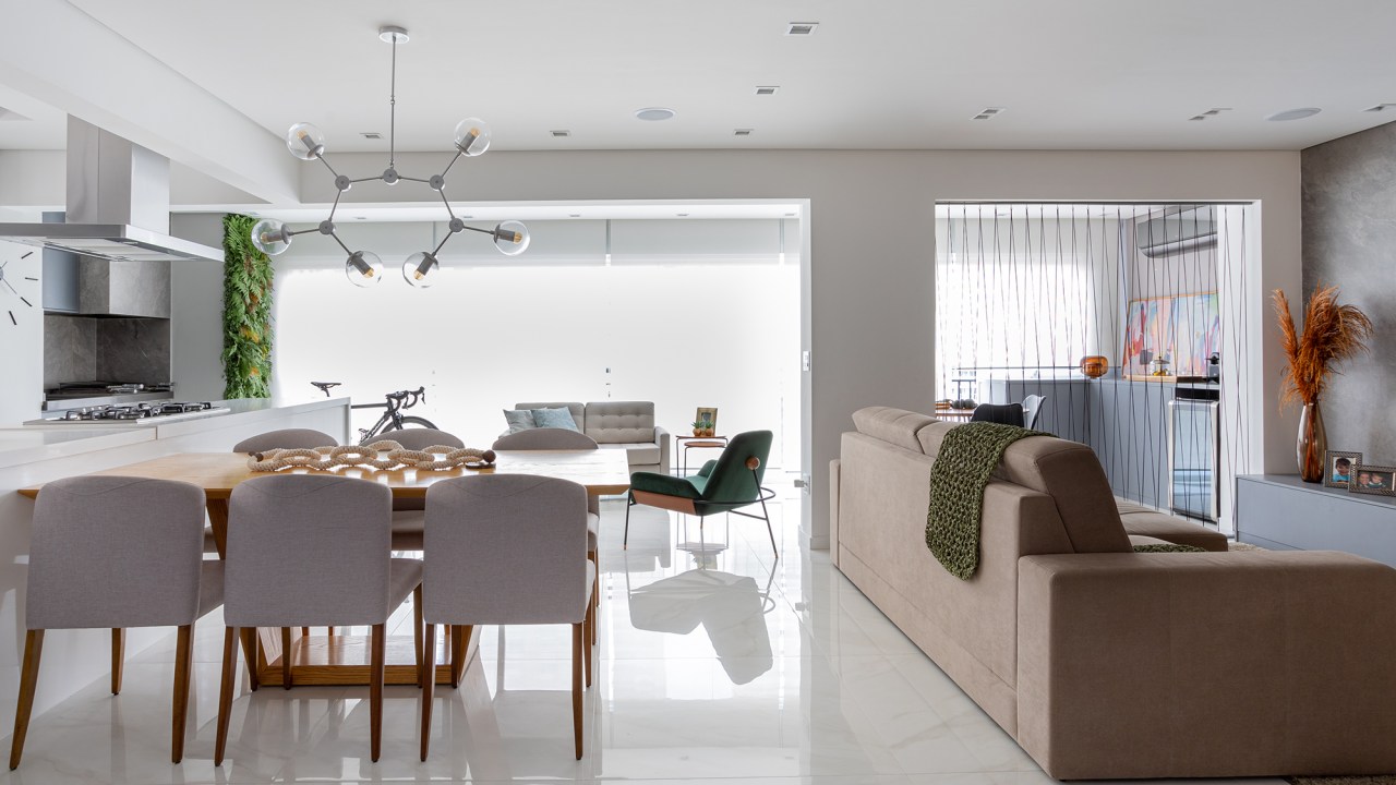 Home office ganha destaque na entrada deste apê de 147 m². Projeto de Bruna Bittencourt. Na foto, sala de estar, jantar e varanda integrados. Parede verde, sofá, mesa e poltronas.