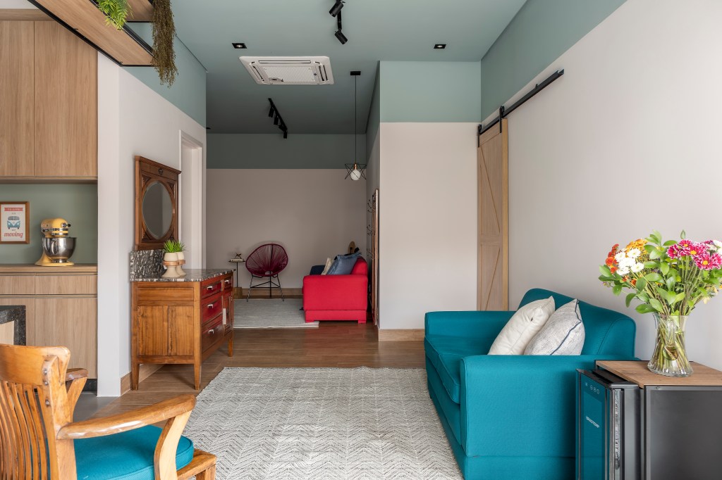 Ideias para usar móveis antigos no décor contemporâneo. Projeto de Carina Dal Fabbro. Na foto, sala de estar com teto azul claro e sofá azul.