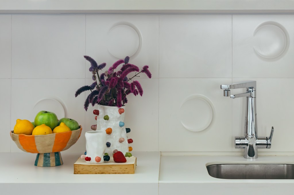 Projeto de Casa Cururu Arquitetura. Na foto, bancada de cozinha branca com fruteira e vaso colorido.