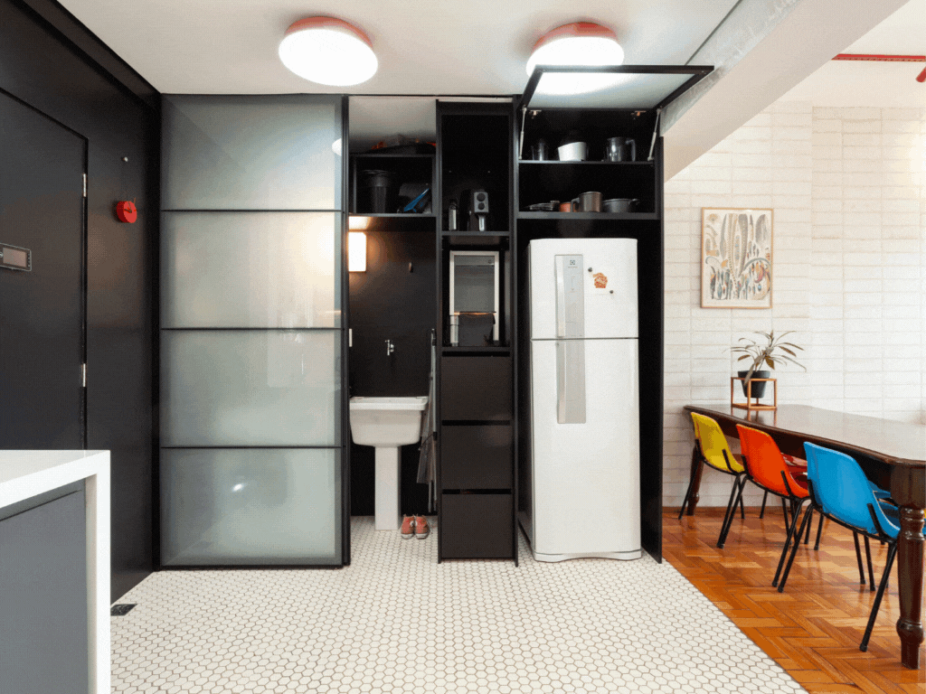 Estilo industrial e móveis retrô marcam apê de 75 m² em Belo Horizonte. Projeto de Mutabile Arquitetura. Na foto, cozinha e lavanderia com parede preta e porta de correr.