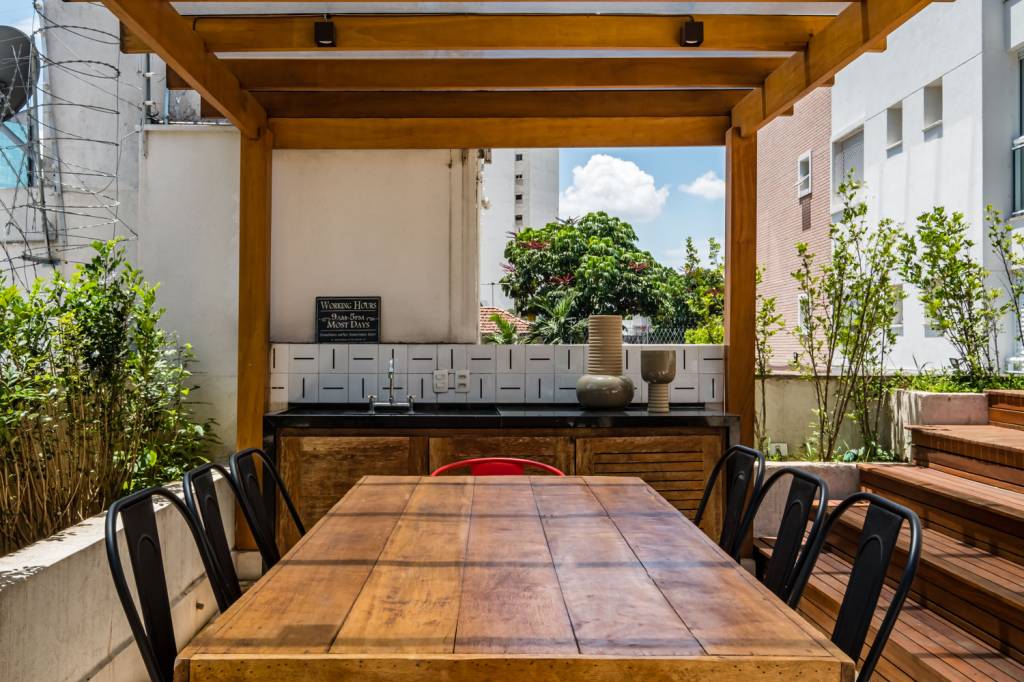 Ôfuro, área gourmet e lareira compõem este apartamento garden de 173 m². Projeto de Ocanhas Arquitetura e Sandra Steuer Arquitetura. Na foto, espaço gourmet no terraço com pergolado.