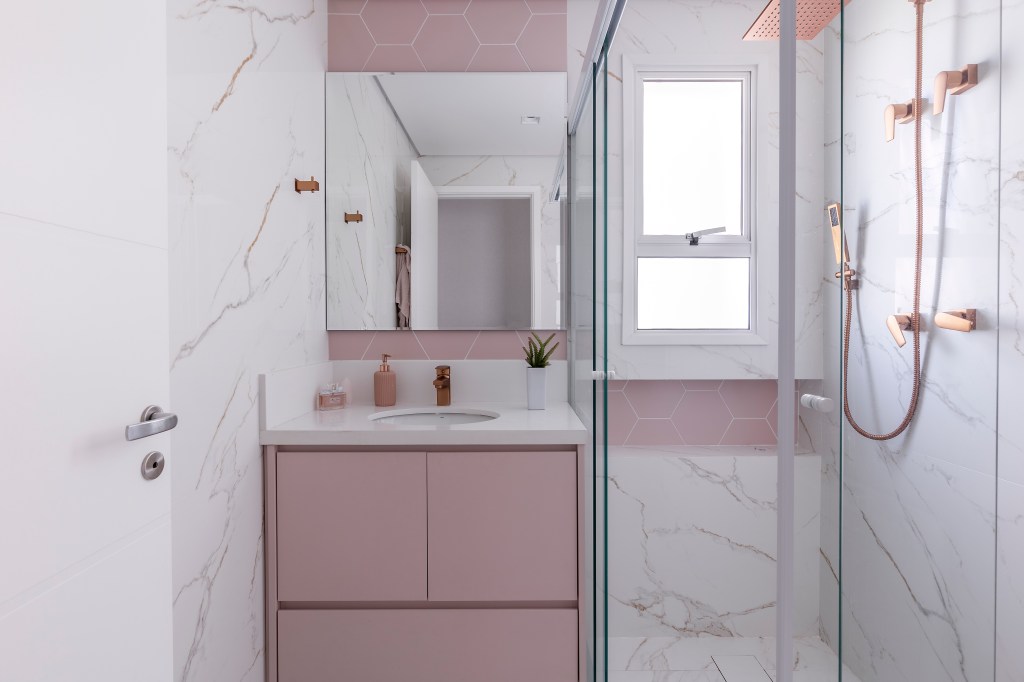 Painel ripado e marmorizado em pé-direito duplo é destaque em apê de 240m². Projeto de Marta Martins. Na foto, banheiro com marcenaria e parede rosa.