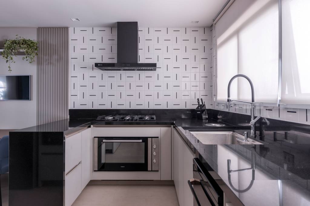 Painel ripado e marmorizado em pé-direito duplo é destaque em apê de 240m². Projeto de Marta Martins. Na foto, cozinha com layout L e parede de azulejos.