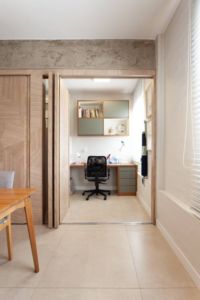 Cada parede sala é de uma cor neste apê de 80 m² com dois home offices. Projeto de Mutabile Arquitetura. Na foto, home office integrada à sala com porta camarão.