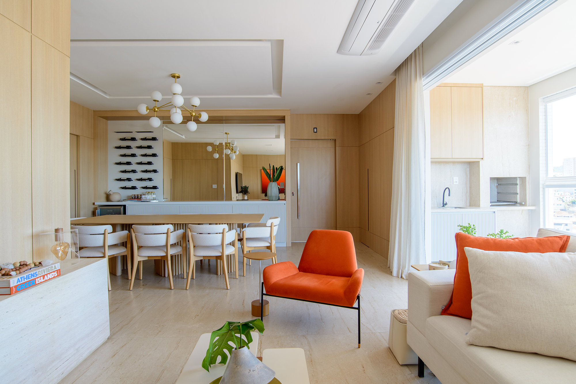 Paredes de madeira e tons de laranja compõem o décor deste apê de 138 m². Projeto de Letícia Nannetti. Na foto, sala, varanda e jarntar integrados. Varanda com churrasqueira e adega.