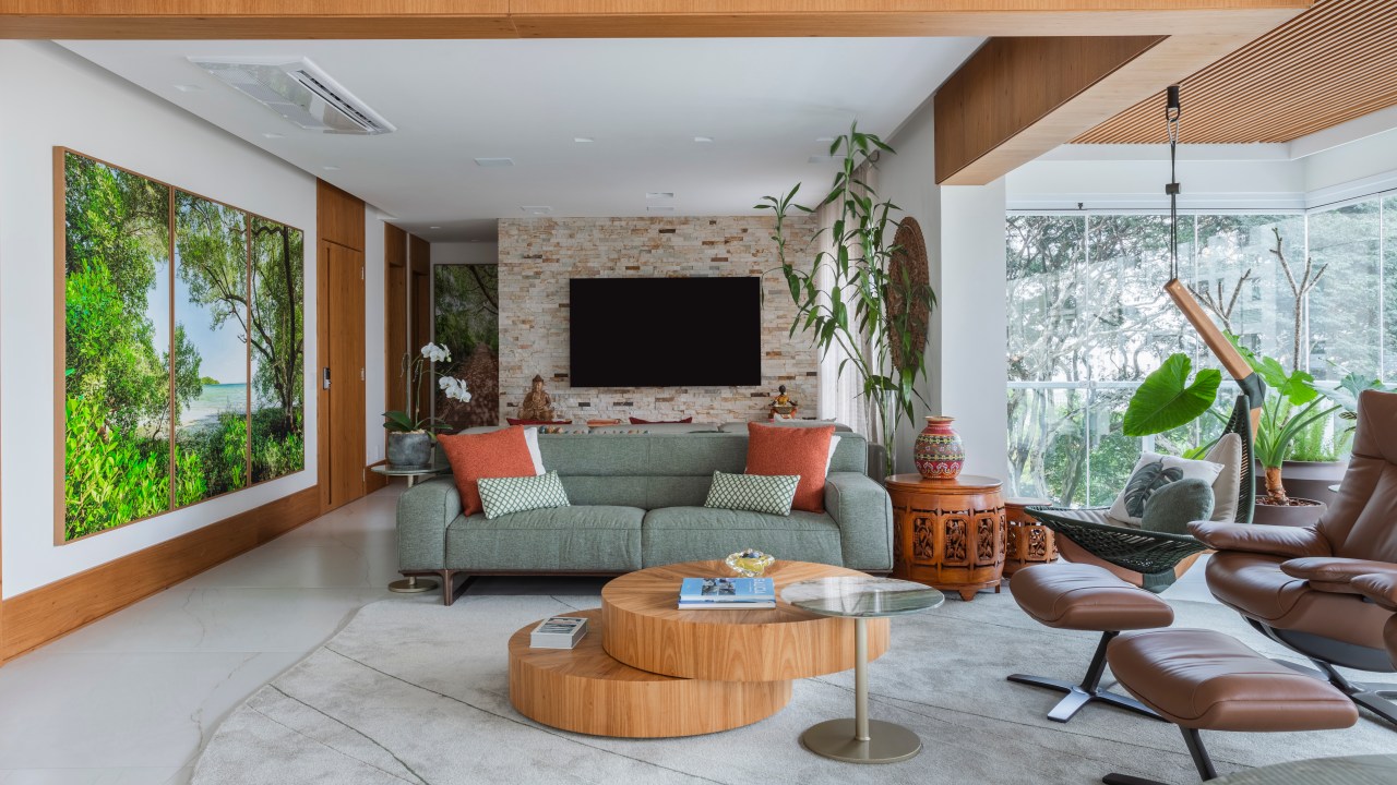 Projeto de Tatu Arquitetura. Na foto, sala de estar integrada com sofá verde, tapete cinza e mesa de centro de madeira.