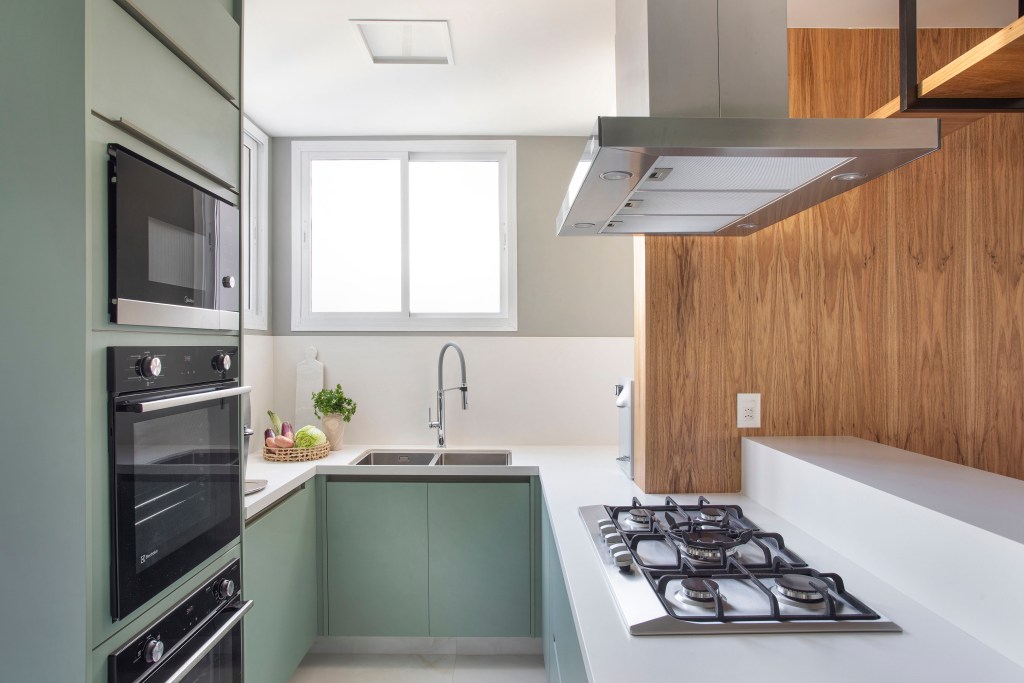 Projeto de Henrique Ramalho. Na foto, cozinha pequena em forma de U com armários verdes.