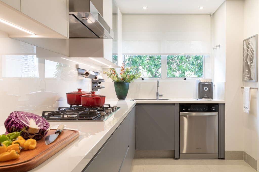 Projeto de Fernanda Dabbur. Na foto, cozinha com bancada branca e marcenaria cinza.