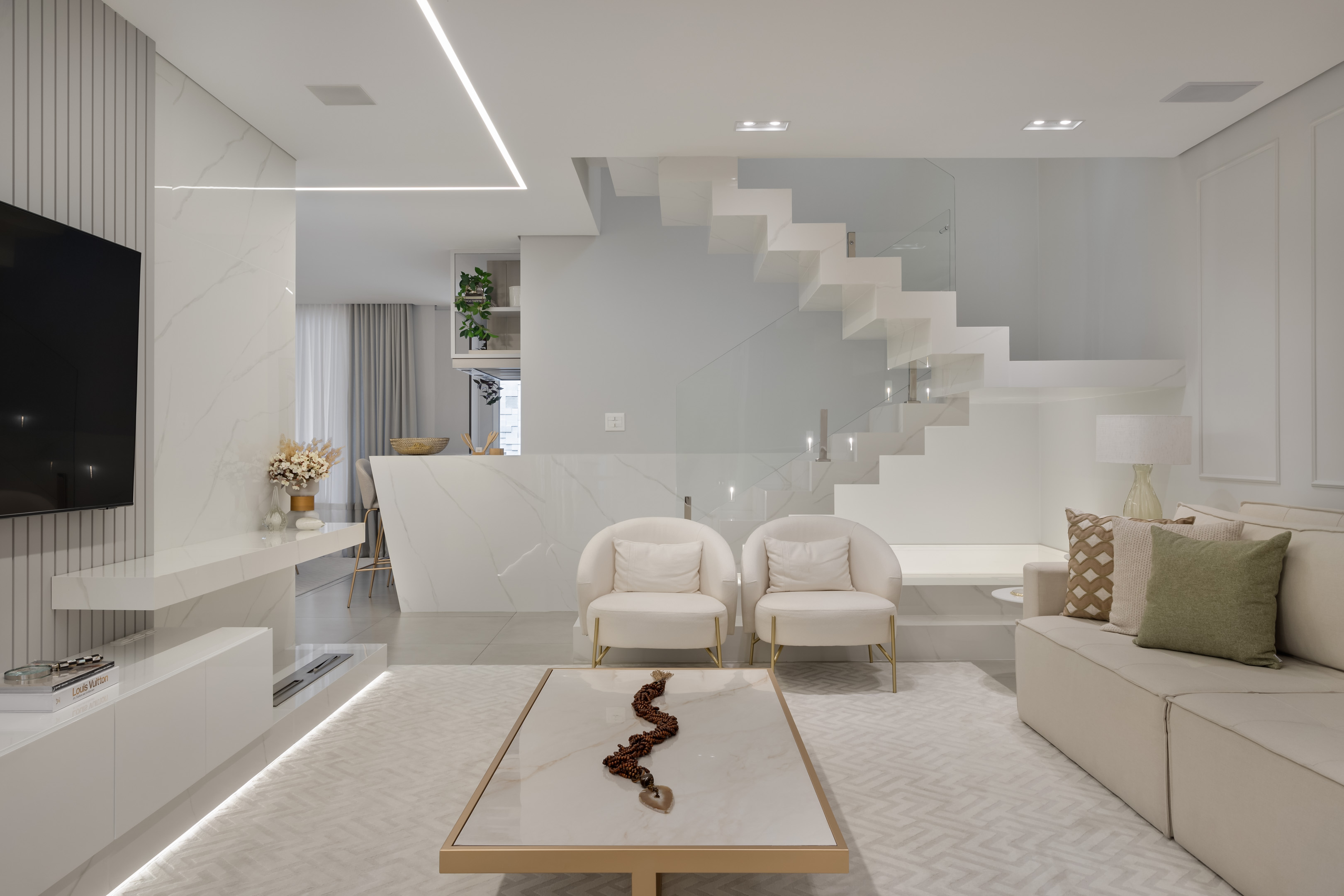 Sem muito quebra-quebra, casa de 205 m² ganha décor clássico e sofisticado. Projeto Carol Dallagrana. Na foto, sala de estar com tv, escada e decor branco.