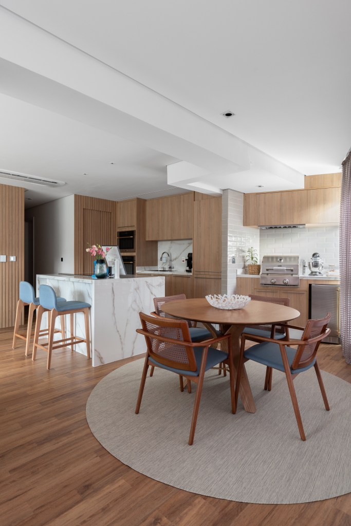 Projeto de CC5 arquitetura e interiores. Na foto, cozinha integrada com sala de jantar com mesa redonda.