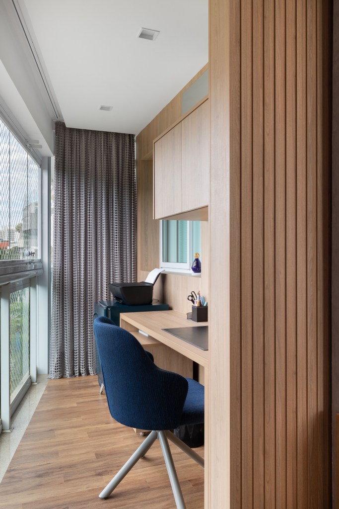 Projeto de CC5 arquitetura e interiores. Na foto, home office com bancada de madeira e cadeira estofada azul.